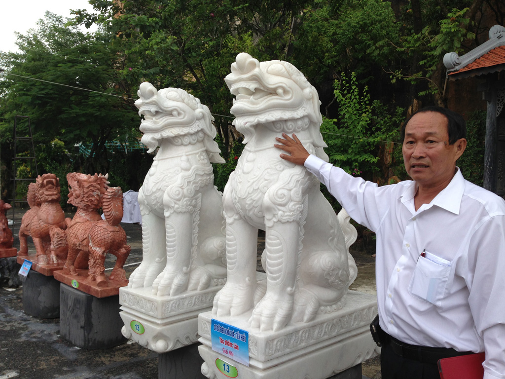 Chủ cơ sở điêu khắc Tiến Hiếu bên tác phẩm lân và nghê đoạt giải nhì và ba - Ảnh: Nguyễn Tú