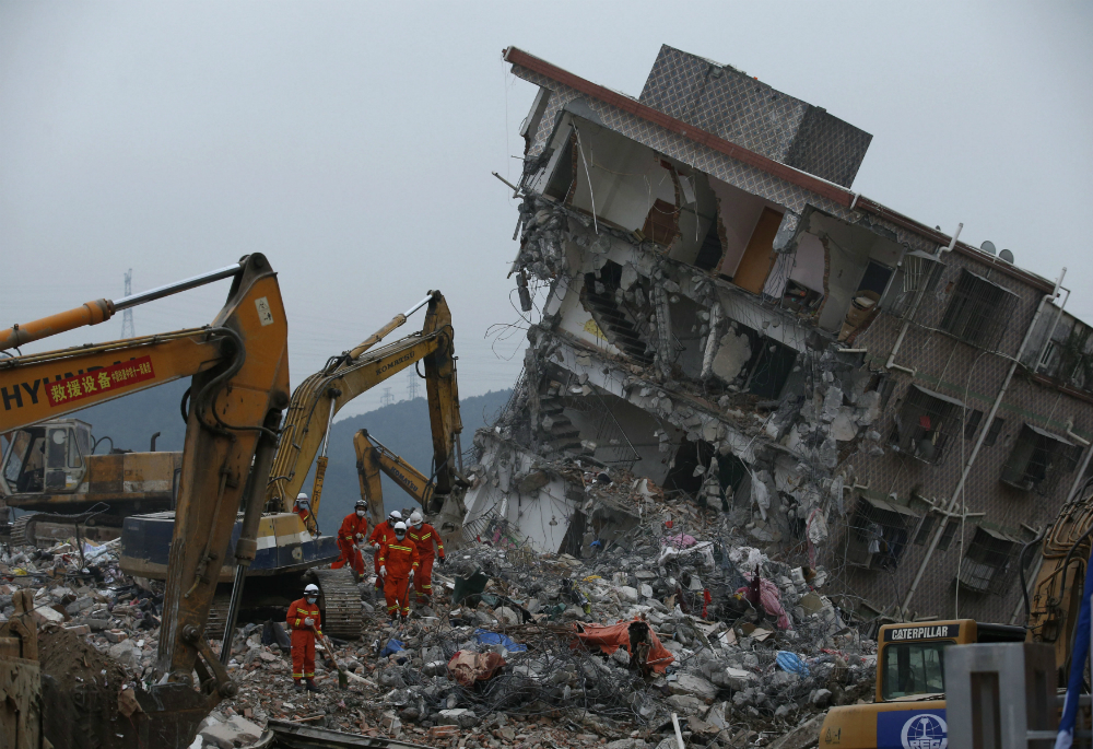Nhân viên cứu hộ tại một căn nhà bị sập vì lở đất - Ảnh: Reuters