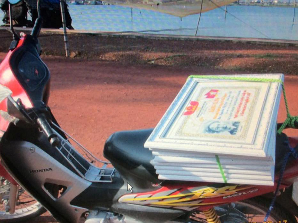Chở bảng vàng đi giao bằng xe máy - Ảnh: Đoàn Thị