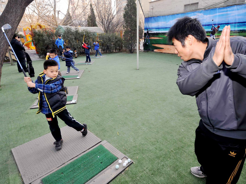 Một cậu bé tập đánh golf ở Bắc Kinh - Ảnh: AFP