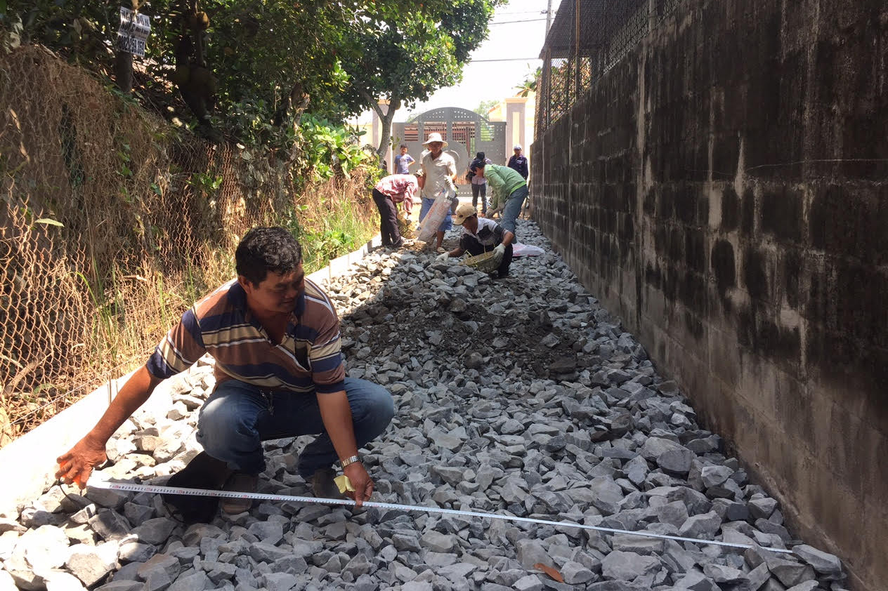Con đường trước nhà mẹ VNAH Nguyễn Thị Em đang được thợ đo đạc, đổ đá - Ảnh: Tuyết Anh