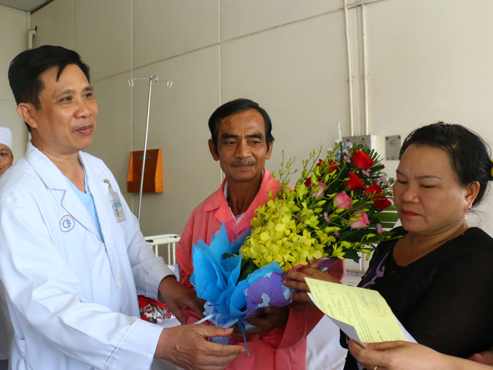 Bác sĩ Trần Quyết Tiến, Phó giám đốc Bệnh viện Chợ Rẫy, tặng hoa, dặn dò ông Nén (giữa) khi xuất viện - Ảnh: Nguyên Mi