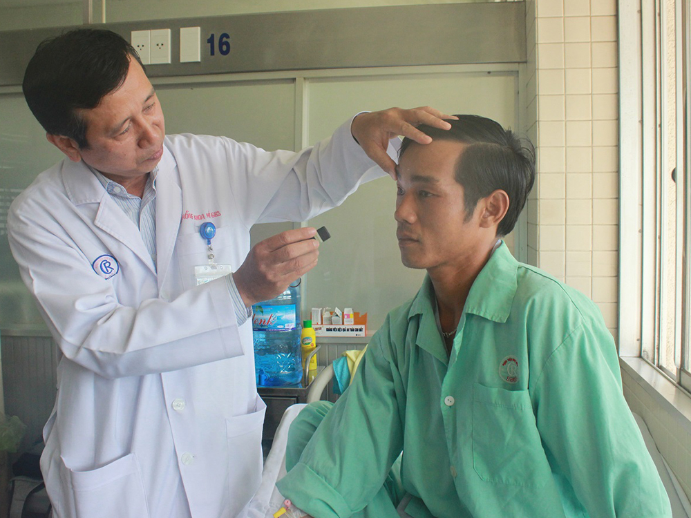Bác sĩ chuyên khoa II Ngô Văn Hồng kiểm tra mắt cho bệnh nhân sau khi được ghép giác mạc - Ảnh: Nguyên Mi