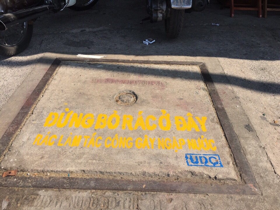 Việc sơn nắp hầm ga nhằm tuyên truyền nhắc nhở người dân không xả rác - Ảnh: Vũ Phượng