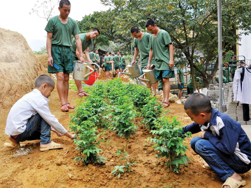 Lý Minh Sơn và Giàng A Sinh chăm sóc vườn rau cùng bộ đội - Ảnh: Mai Thanh Hải