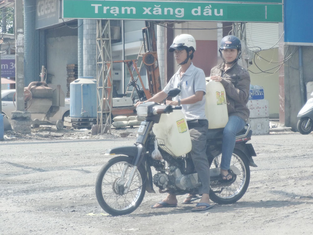 Chị Phương (ngồi sau) trong vai người mua bán xăng lẻ đi trinh sát - Ảnh: Sở KH-CN Đồng Nai