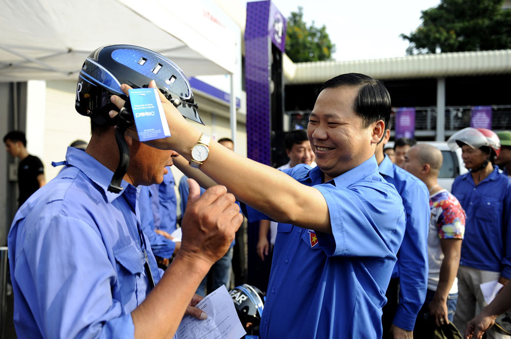 Anh Nguyễn Phi Long tặng mũ bảo hiểm cho tài xế xe ôm tại Bến xe Giáp Bát - Ảnh: P.Hậu