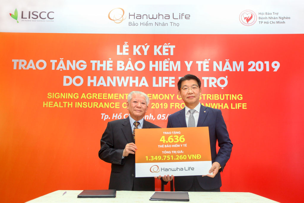 Ông Back Jong Kook, Chủ tịch Hội đồng thành viên kiêm Tổng giám đốc Hanwha Life Việt Nam (bìa phải), trao bảng tài trợ tượng trưng 4.636 thẻ BHYT cho ông Trần Thành Long, Chủ tịch Hội Bảo trợ Bệnh nhân Nghèo TP.HCM ngày 5.3