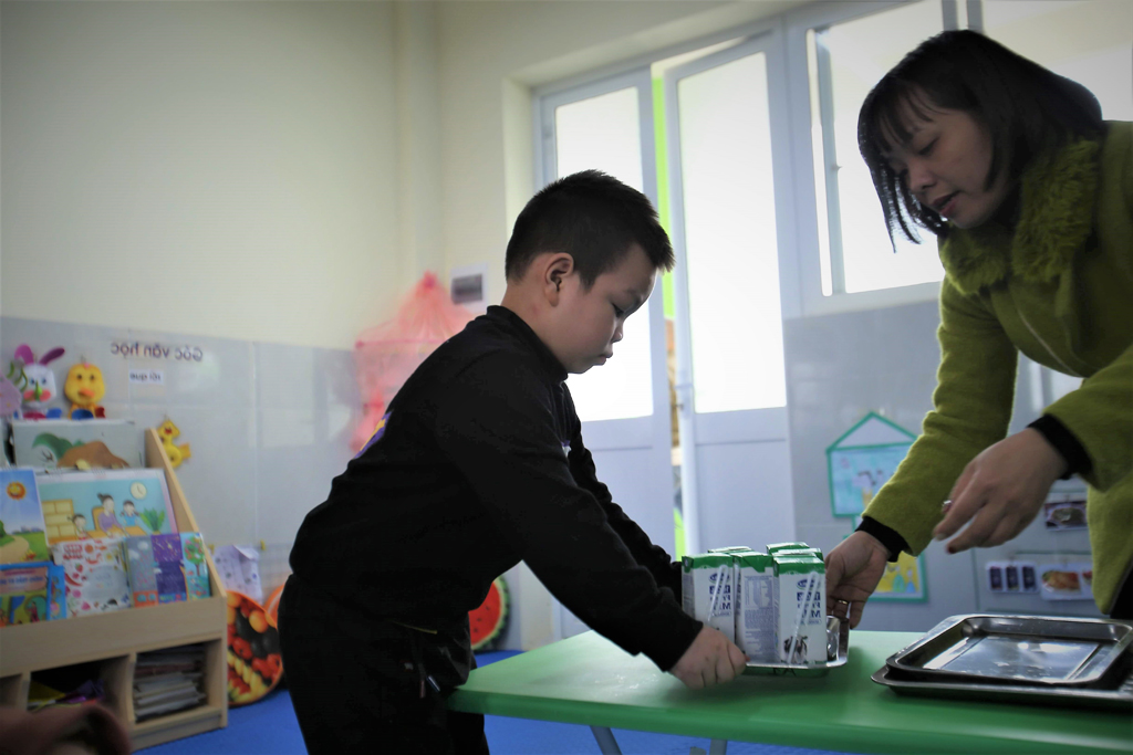 Cô giáo chuẩn bị sữa cho các bé tham gia Chương trình Sữa học đường tại một điểm trường ở Hà Nội