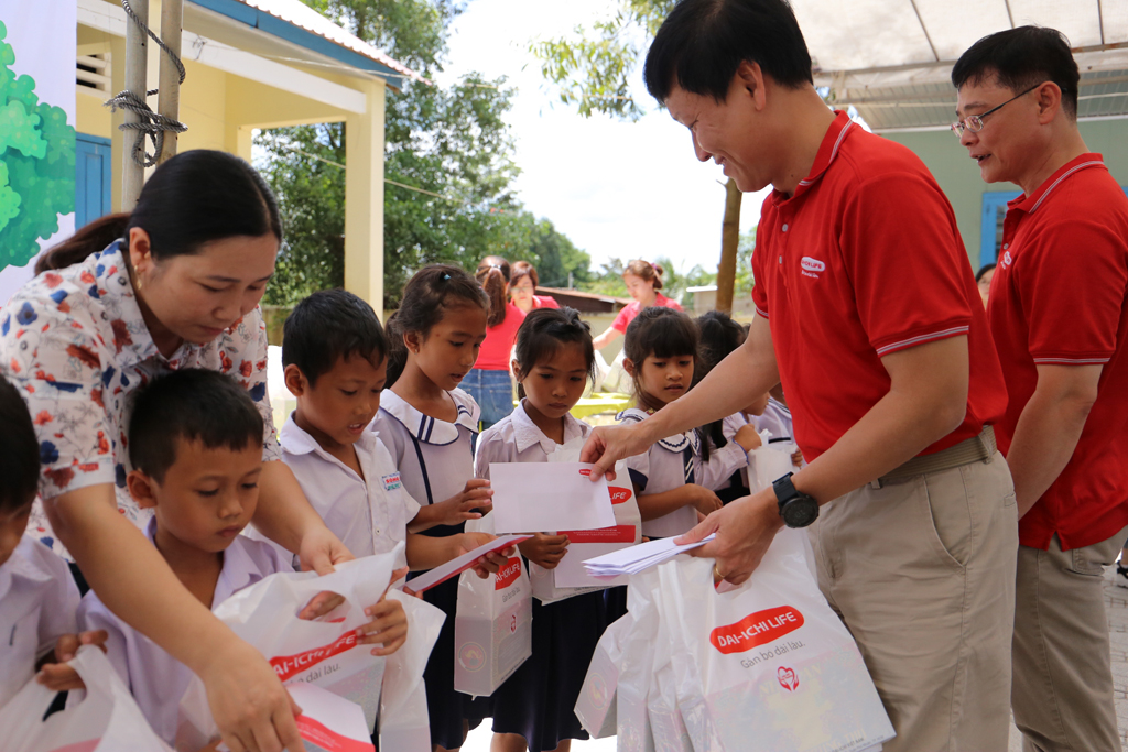 Ông Trần Đình Quân - Tổng giám đốc Dai-ichi Life Việt Nam (áo thun đỏ, thứ 2 từ phải qua) trao học bổng và quà cho các em học sinh