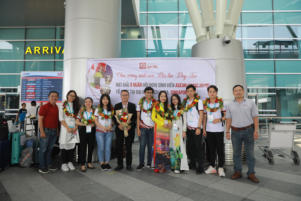 Thầy Bùi Đức Anh (thứ 5 từ trái sang) trực tiếp dẫn đoàn SV ĐH Duy Tân nhận hoa chúc mừng khi về đến sân bay Đà Nẵng