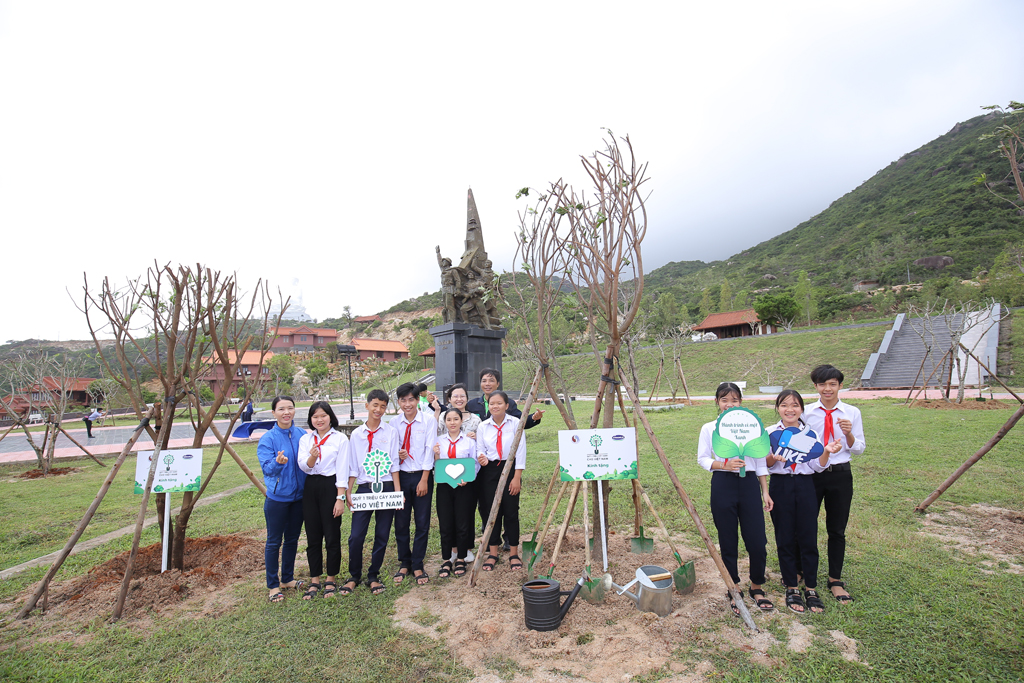 Các em học sinh chụp hình lưu niệm bên những cây xanh vừa được trồng trong chương trình Quỹ 1 triệu cây xanh cho Việt Nam