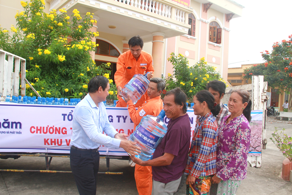 Ông Nguyễn Văn Hợp (bìa trái) trao tặng bình nước ngọt cho người dân vùng hạn mặn tỉnh Bến Tre. Ảnh: Đình Hoàng 