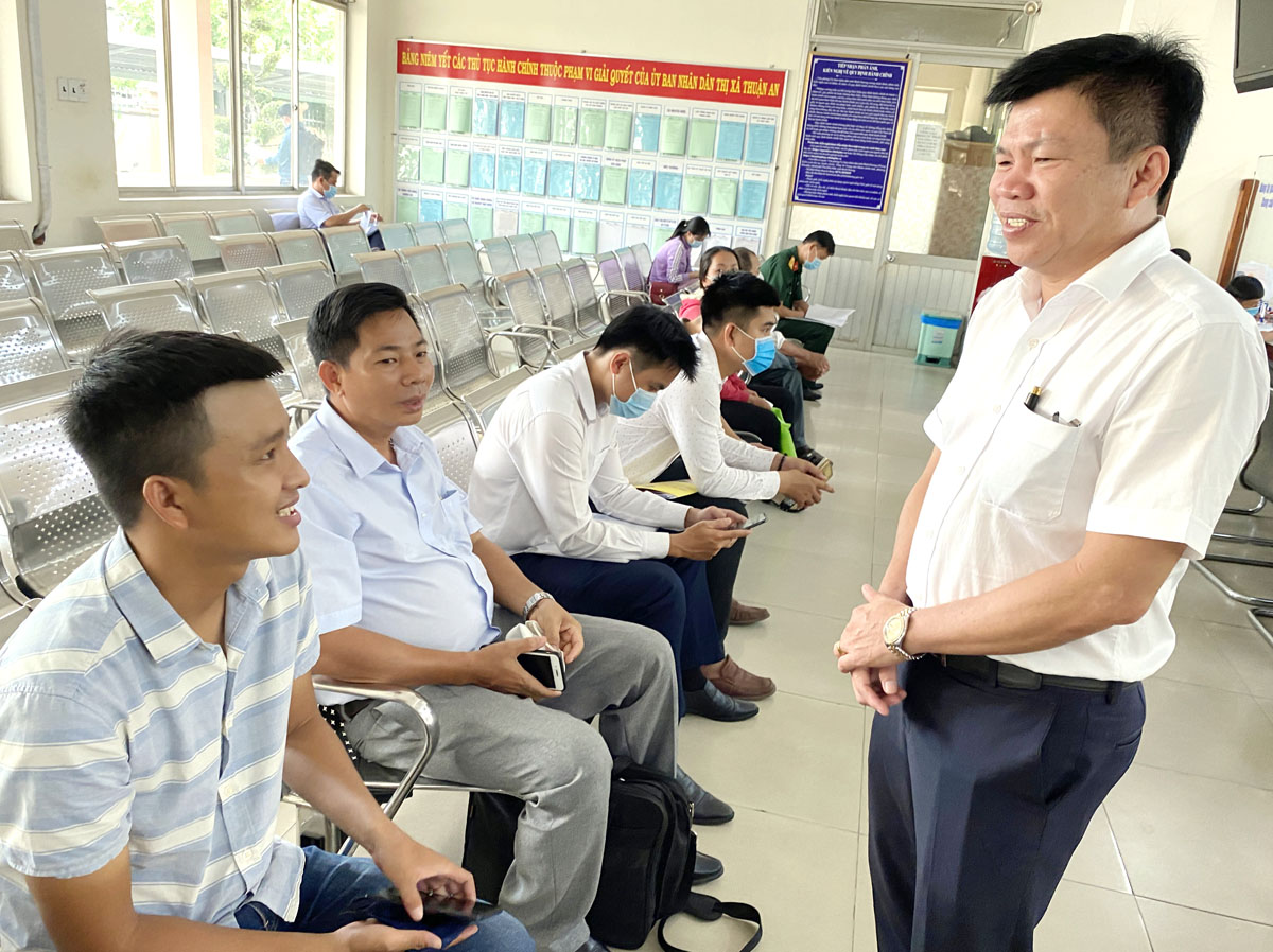 Ông Nguyễn Thanh Tâm (phải) thăm hỏi người dân đến giải quyết thủ tục hành chính