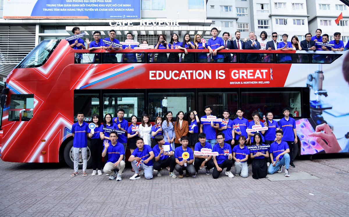 Sinh viên Trường ĐH Greenwich (Việt Nam) chụp ảnh cùng đoàn Lãnh sự quán Anh bên cạnh xe buýt 2 tầng
