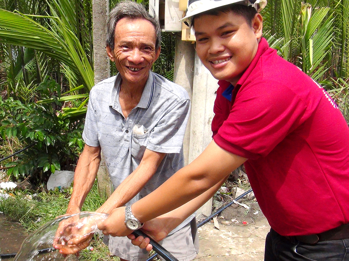Ông Trần Văn Thanh (phải), người dân tổ 8, ấp An Bình, xã An Thới Đông, H.Cần Giờ (TP.HCM) vui mừng khi nước sạch do SAWACO cung cấp vào tới tận nhà mình