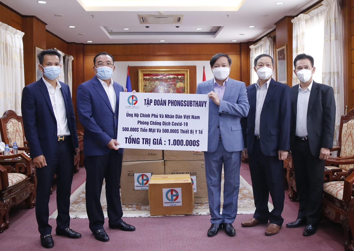 Chủ tịch Tập đoàn Phongsubthavy của Lào, ông Phongsavath Senaphuan (trái) đang trao tượng trưng tấm biển số tiền và vật tư y tế trị giá 1 triệu USD cho Đại sứ Nguyễn Bá Hùng để ủng hộ Quỹ phòng chống Covid-19 của Việt Nam