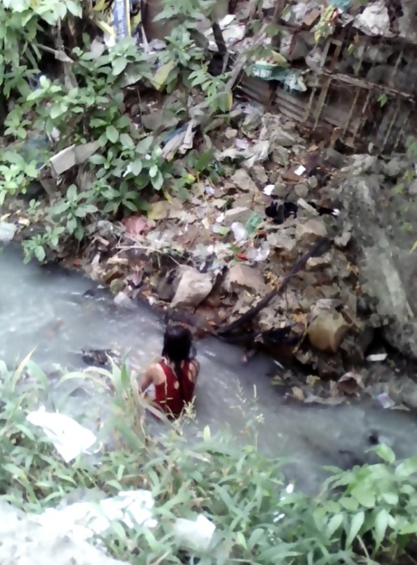 Cô gái có biểu hiện bất thường 'tắm' dưới kênh nước thải - Ảnh: người dân cung cấp