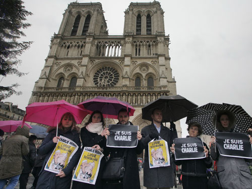 Người dân Pháp đội mưa tưởng niệm nạn nhân vụ khủng bố tòa soạn báo Charlie Hebdo trước nhà thờ Đức bà Paris - Ảnh: AFP