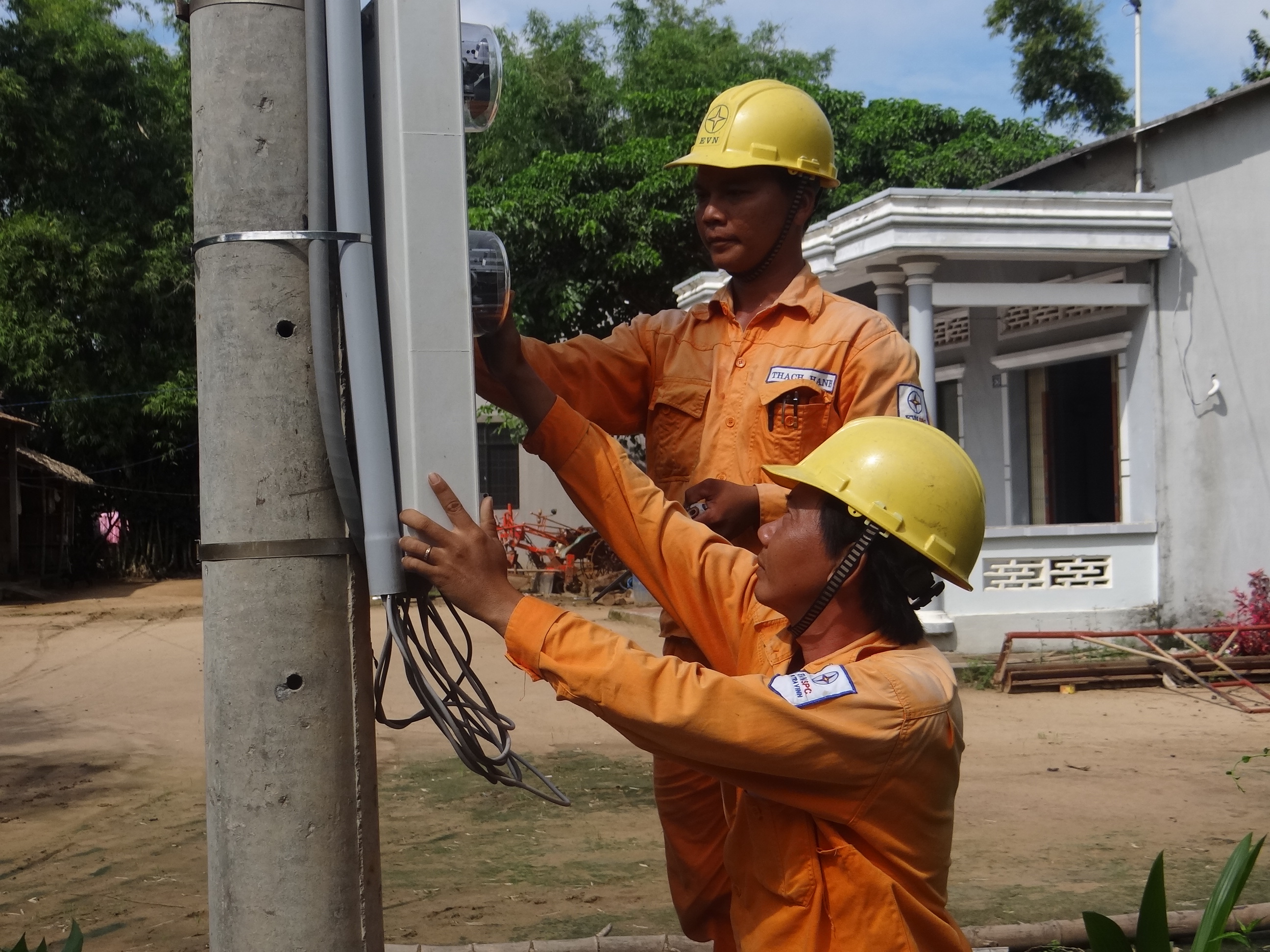 Công nhân Điện lực Duyên Hải lắp đặt điện kế cho các hộ dân thuộc dự án Khmer - Ảnh Huy Hoàng