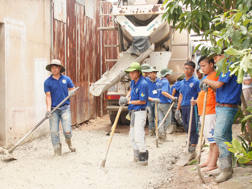 Thanh niên tình nguyện làm đường bê tông cho người dân tại Q.9, TP.HCM - Ảnh: Lê Thanh