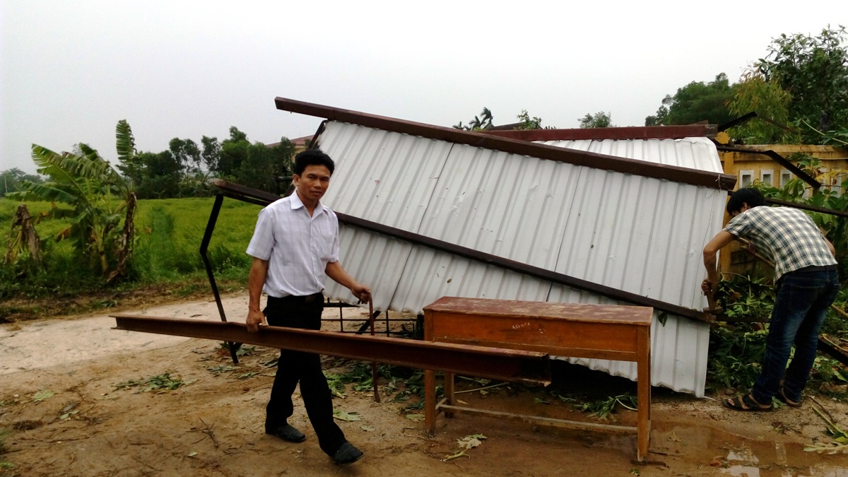 Giáo viên Trường THCS Phong Hiền thu gom những mái tôn bị tốc mái về sửa chữa lợp tạm cho học sinh học - Ảnh: Đình Toàn