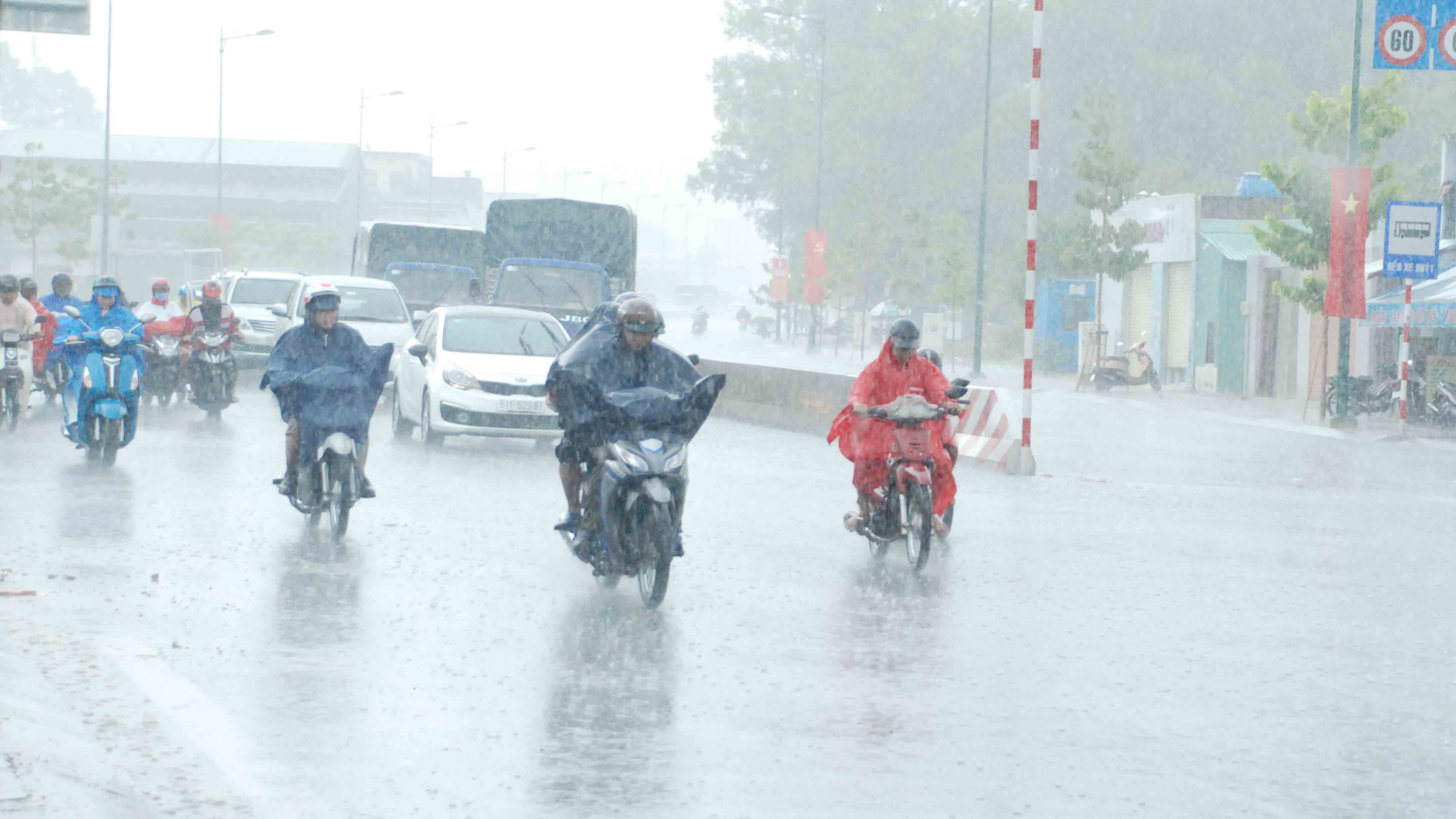 Nhiều người lùng bùng áo mưa đi lại giữa mưa lớn trên đường Phạm Văn  Đồng - Ảnh: An Huy