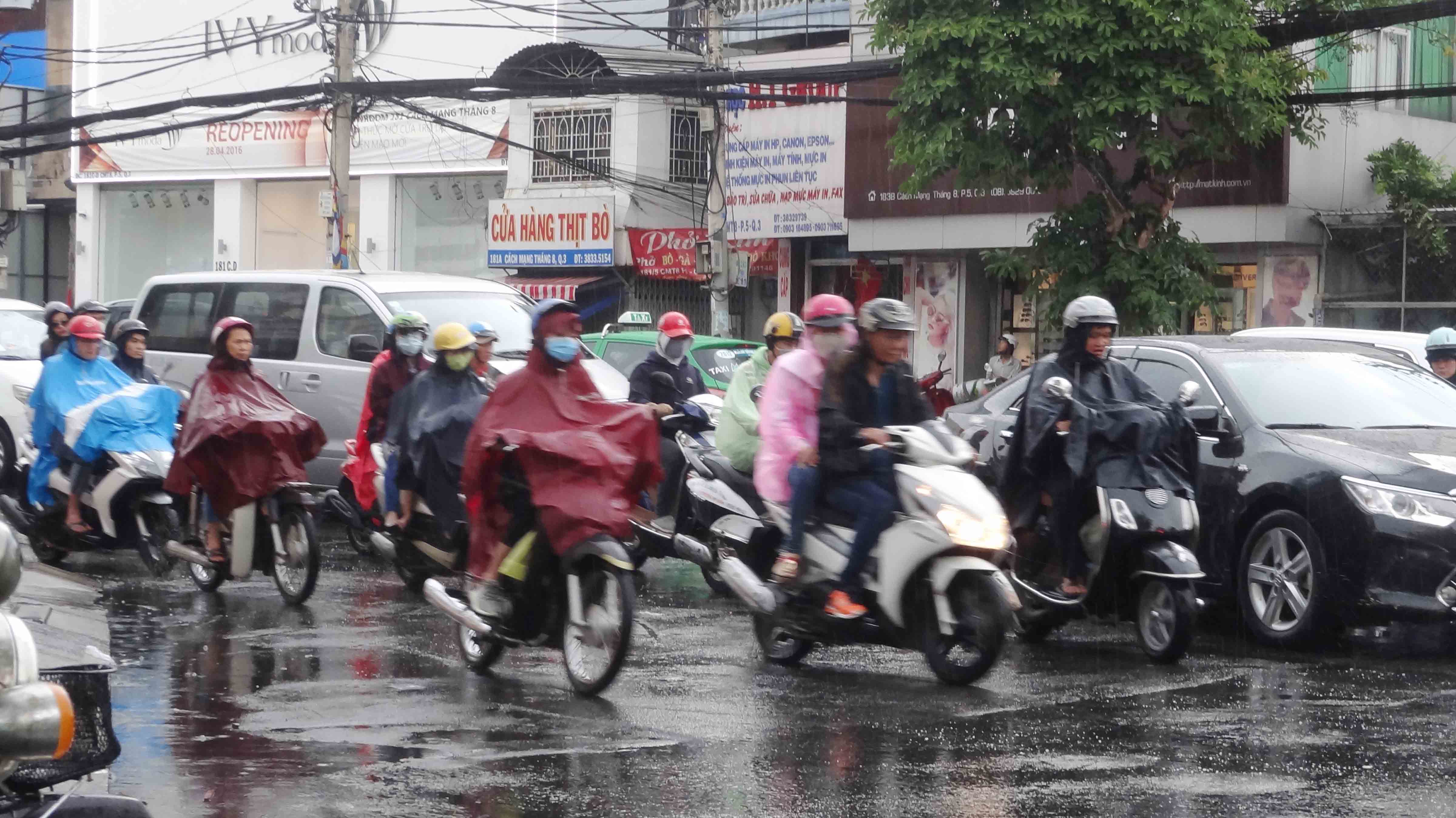 Nhiều người lùng bùng áo mưa đi lại trên đường Cách Mạng Tháng Tám (Q.3) - Ảnh: An Huy