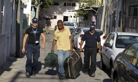 Một người nhập cư được 2 cảnh sát Israel 'tiễn' ra sân bay - Ảnh: Reuters