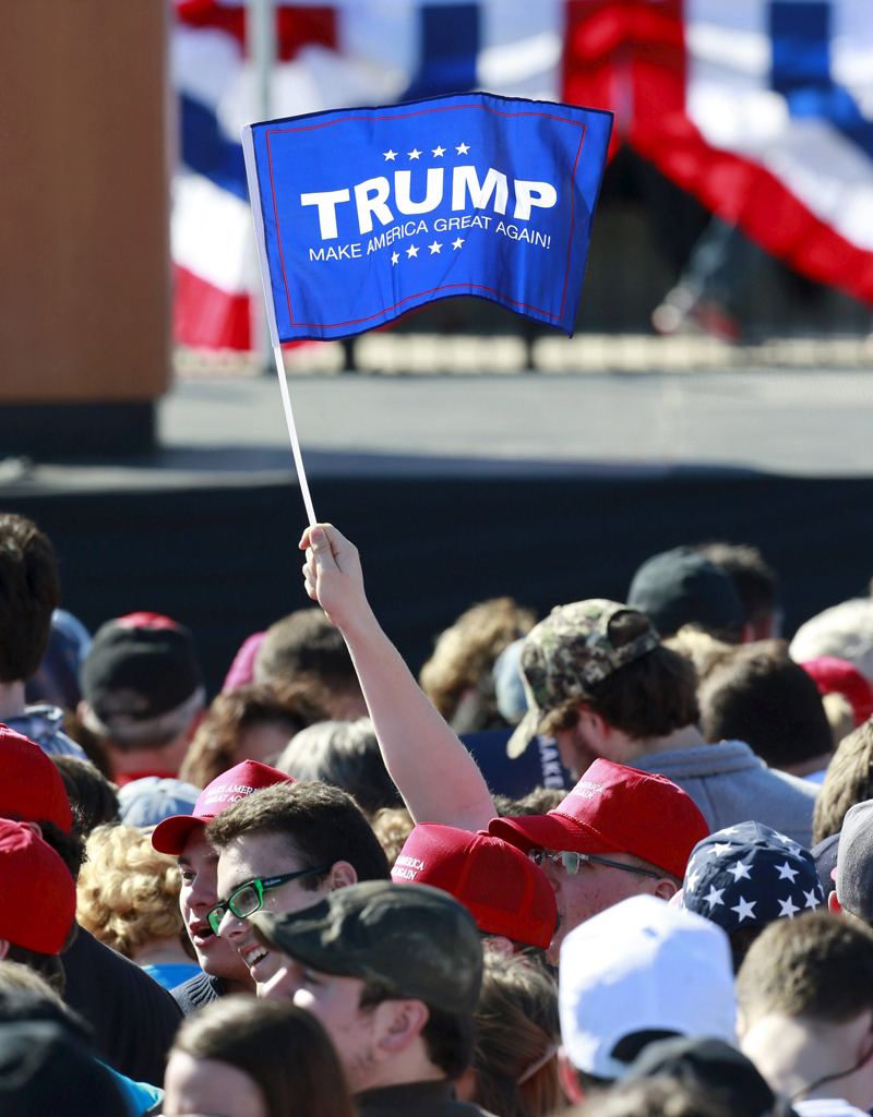 Một ủng hộ viên của tỉ phú Trump giương cao lá cờ mang tên ông - Ảnh: Reuters