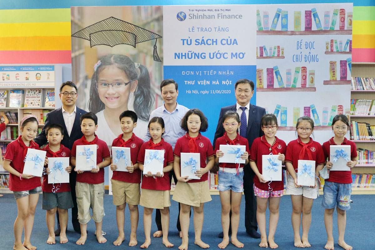Ông Trần Văn Hà, Giám đốc Thư viện Hà Nội và Đại diện Ban Giám đốc Shinhan Finance trao quà cho các em học sinh