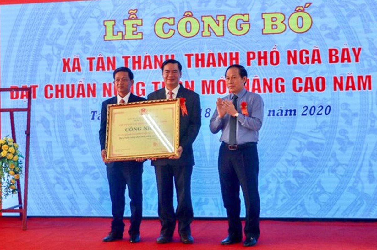 Ông Lê Tiến Châu (bìa phải) trao quyết định công nhận xã NTM nâng cao