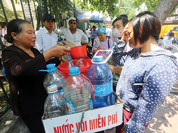 Bà Thụng đang phát nước vối miễn phí cho bệnh nhân và người nhà họ trước cổng Bệnh viện K Hà Nội 