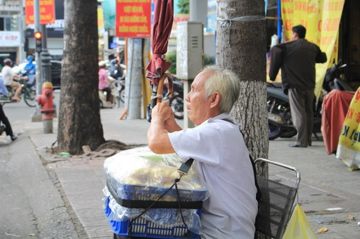 Ông Quang tự cột dù để che nắng che mưa.