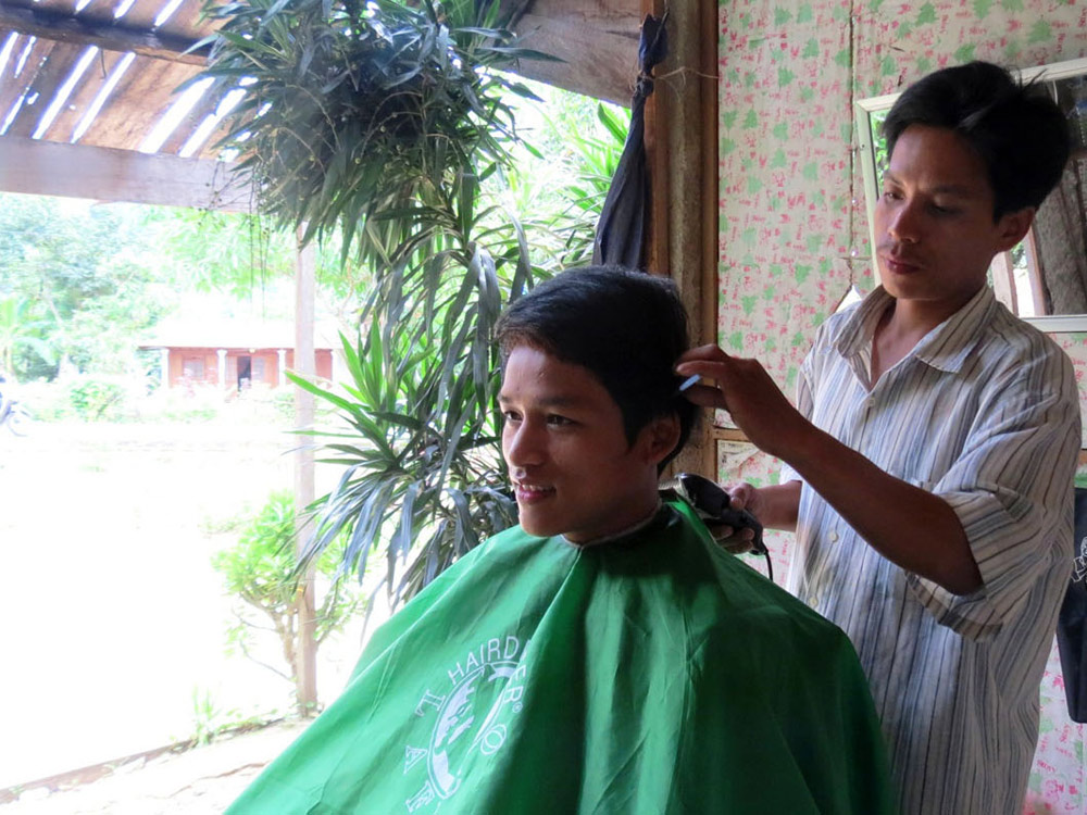 Anh Hồ Văn Dâm đang cắt tóc để thêm thu nhập nuôi con cái học hành 