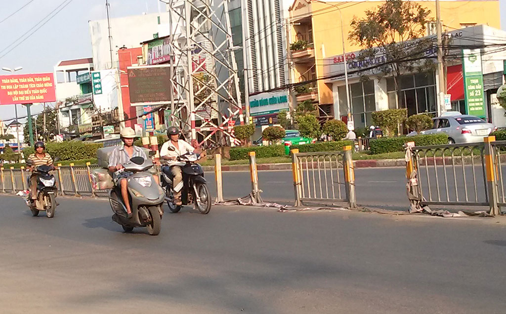 Người dân phá tấm chống lóa để băng qua QL1A - Ảnh: Nguyên Dũng