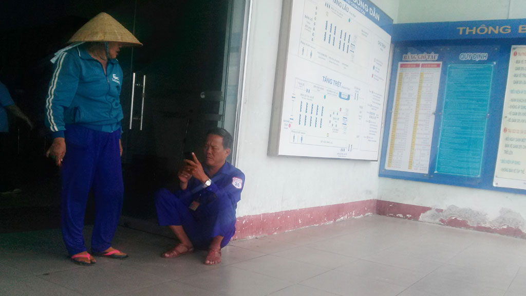 Ông Nguyễn Tiến Khanh ngồi trước cửa ra vào nhà chờ ga, tránh nắng và hỏi thăm khách đi xe ôm.