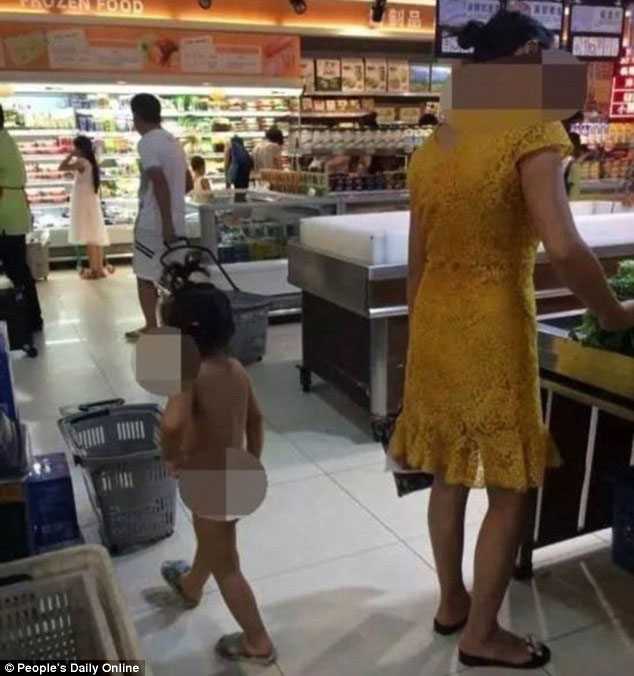 Cô bé không áo quần quanh quẩn bên mẹ ở siêu thị