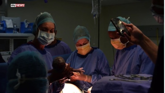 Có tới 20 bác sĩ phẫu thuật, bác sĩ gây mê và y tá hỗ trợ ca sinh 3 của cặp đồng tính nam này - Ảnh chụp video SkyNews