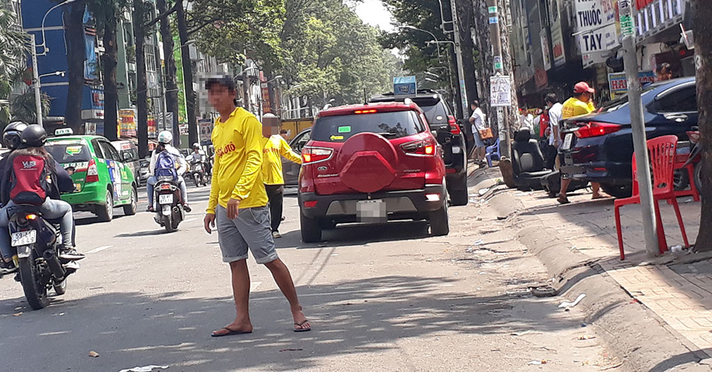 Nhân viên một cửa hàng sửa chữa và buôn bán phụ kiện ô tô trên đường An Dương Vương (Q.5) tràn ra chiếm khu vực đậu xe có thu phí để bắt khách ảnh: TIỂU THIÊN