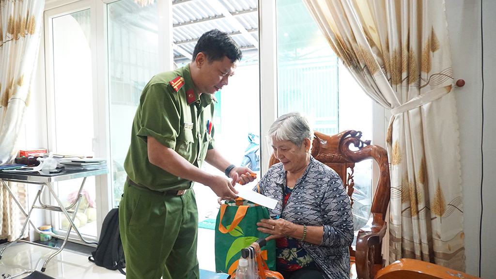 Trung tá Võ Hướng Nam trao quà Tết của đơn vị cho bà Cúc.Huyền Mai