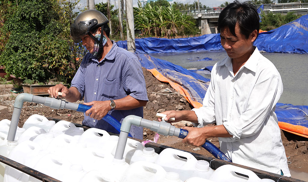 Nhà vườn hối hả đến lấy nước về cứu vườn sầu riêng khô hạn Ảnh: Bắc Bình