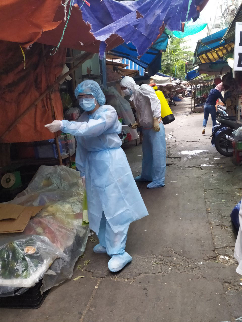 Bác sĩ Bùi Thị Thanh Hải (trước), Trưởng trạm y tế P.5 (Q.11), đi phun thuốc khử khuẩn khu vực có ca bệnh Ảnh: CTV