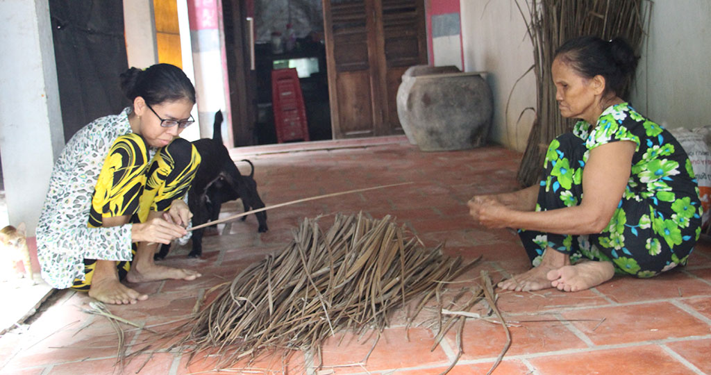 Chị Hoa phụ tiếp mẹ lặt cọng dừa đem bán kiếm tiền trang trải cuộc sống hàng ngày của hai mẹ con ẢNH: DUY TÂN