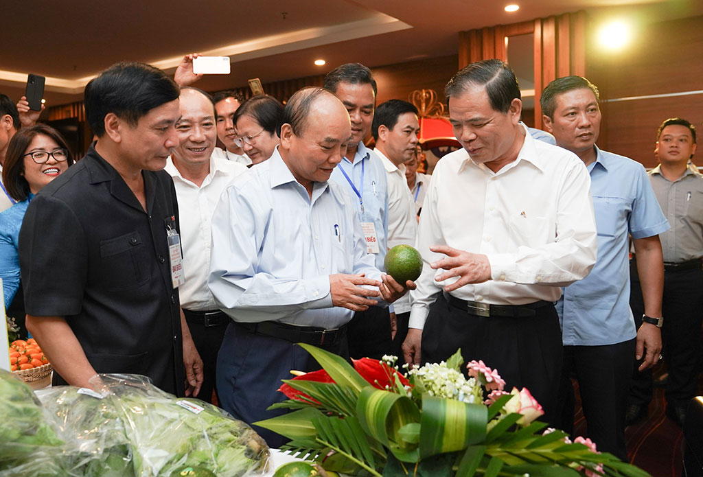 Thủ tướng nghe Bộ trưởng Bộ NN-PTNT Nguyễn Xuân Cường (bên phải) giới thiệu một số loại nông sản tiêu biểu ẢNH: QUANG HIẾU
