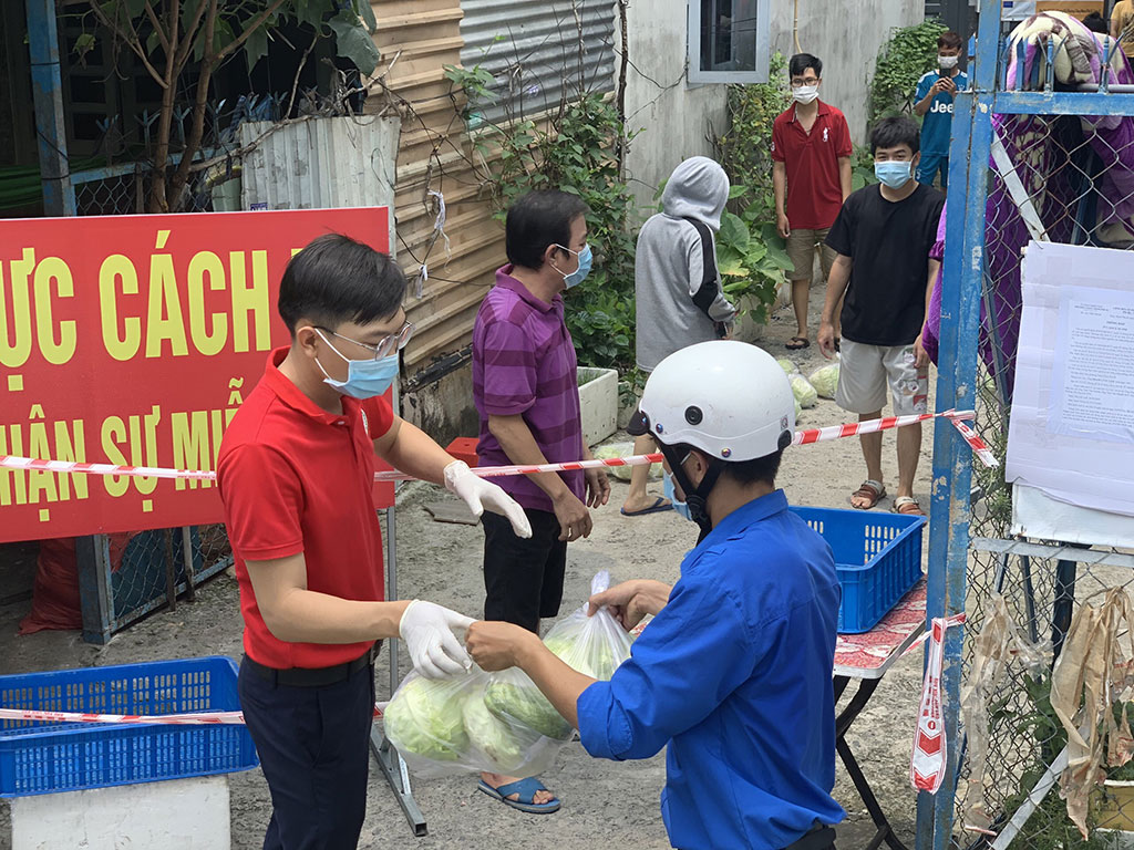 Thanh niên tình nguyện ở TP.HCM trao những phần quà rau xanh, nhu yếu phẩm cho người dân khu vực phong tỏa ẢNH: LÊ THANH