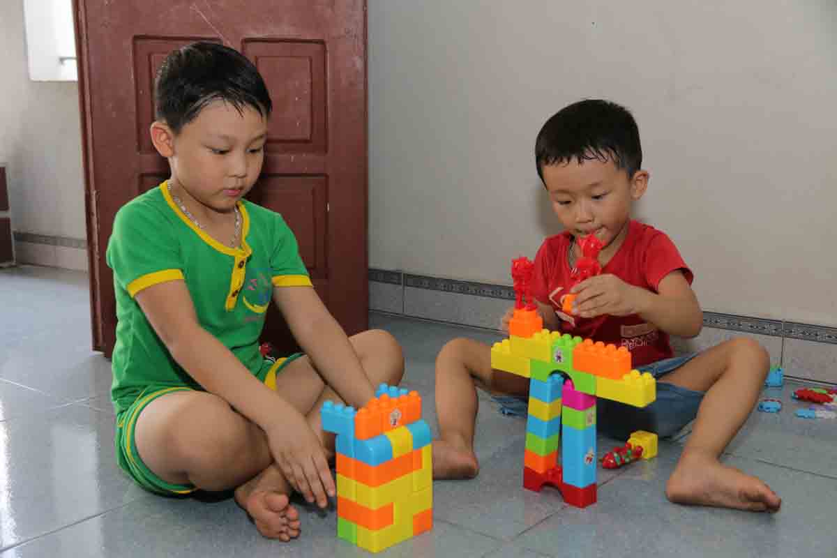 Cậu bé Nguyễn Thiên Long (trái) cùng em trai Nguyễn Thiên Phong (phải) đang hăng say xây dựng các tòa nhà trên mô hình lắp ráp