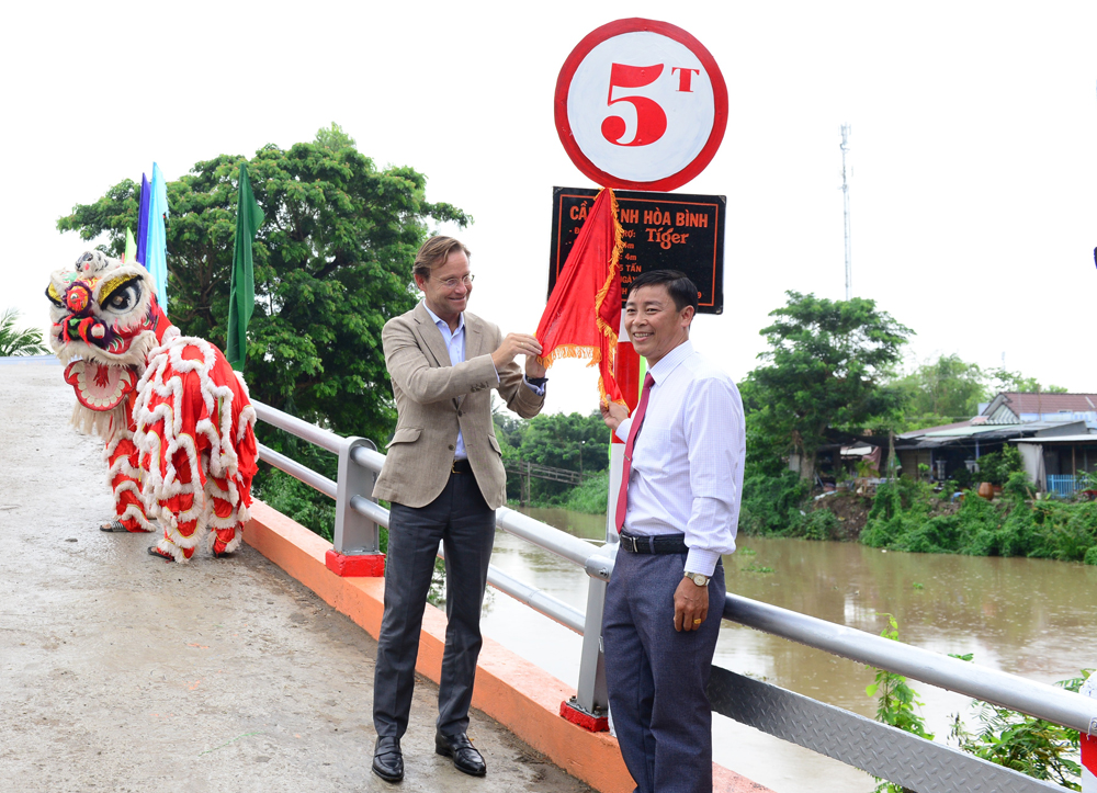 Ông Jacco van der Linden, Tổng giám đốc Điều hành HEINEKEN Việt Nam (bên trái) cùng đại diện huyện Phú Tân cùng kéo vải tấm biển khánh thành cây cầu Kênh Hòa Bình 