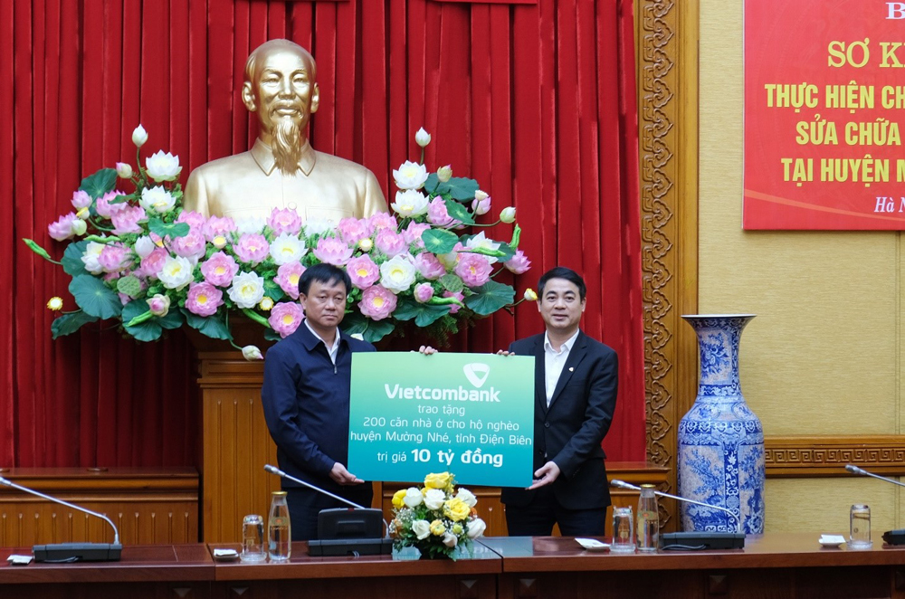 Đồng chí Nghiêm Xuân Thành, Bí thư Đảng ủy, Chủ tịch HĐQT Vietcombank (bên phải) trao biển tượng trưng 10 tỉ đồng kinh phí ủng hộ thực hiện chủ trương xây dựng, sửa chữa nhà cho 200 hộ nghèo tại huyện Mường Nhé, tỉnh Điện Biên