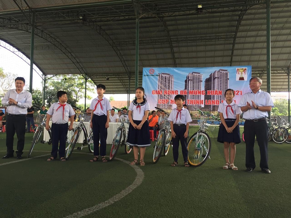 Ông Cao Tiến Dũng (bìa phải) và ông Nguyễn Nam Hiền, Phó tổng giám đốc Tập đoàn Hưng Thịnh trao xe đạp cho học sinh nghèo, vượt khó